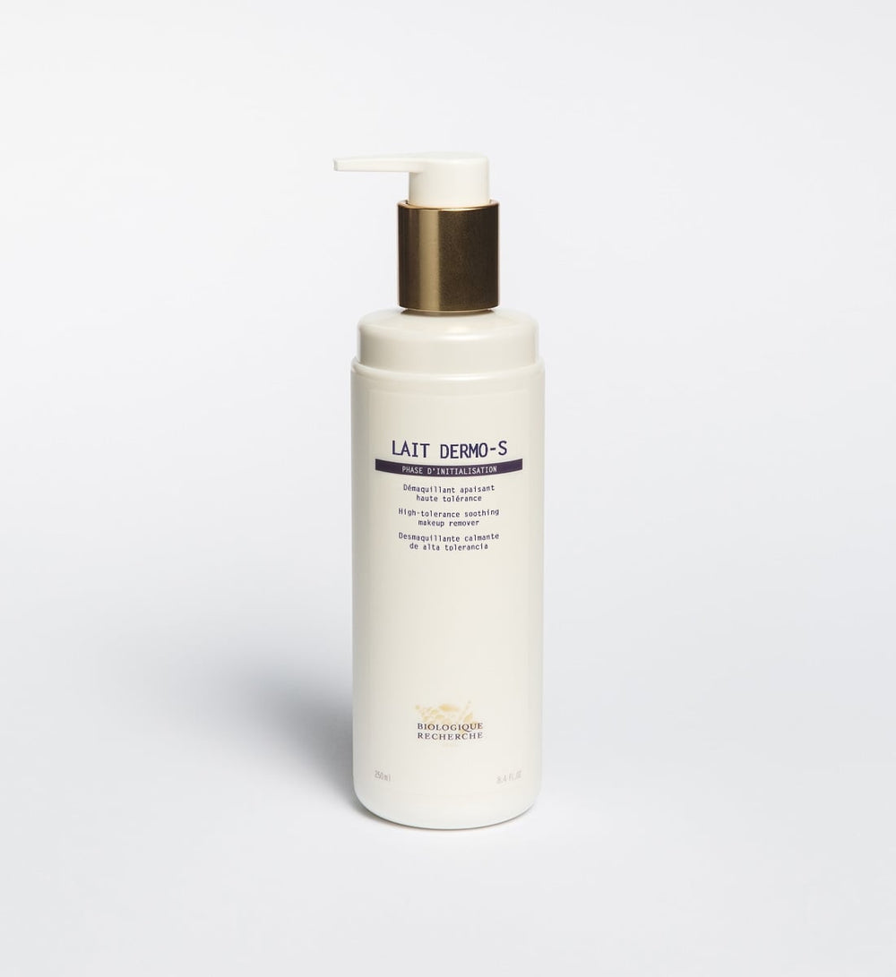 The Biologique Recherche Lait Dermo-S, a white pump bottle with gold accents, stands on a white background, offering a soothing formula ideal for sensitive skin.