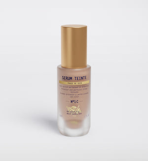 A Biologique Recherche Serum Teinte N1 Cold bottle with a gold cap is displayed on a white background, highlighting its photo-protection qualities. The bold "Noir" on the label is surrounded by French text.