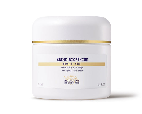 The white jar of Biologique Recherche Crème Biofixine is an anti-aging face cream with advanced myorelax peptide technology and a gold band near the lid. It holds 50 ml (1.7 fl. oz.) and is designed to smooth fine lines effortlessly.