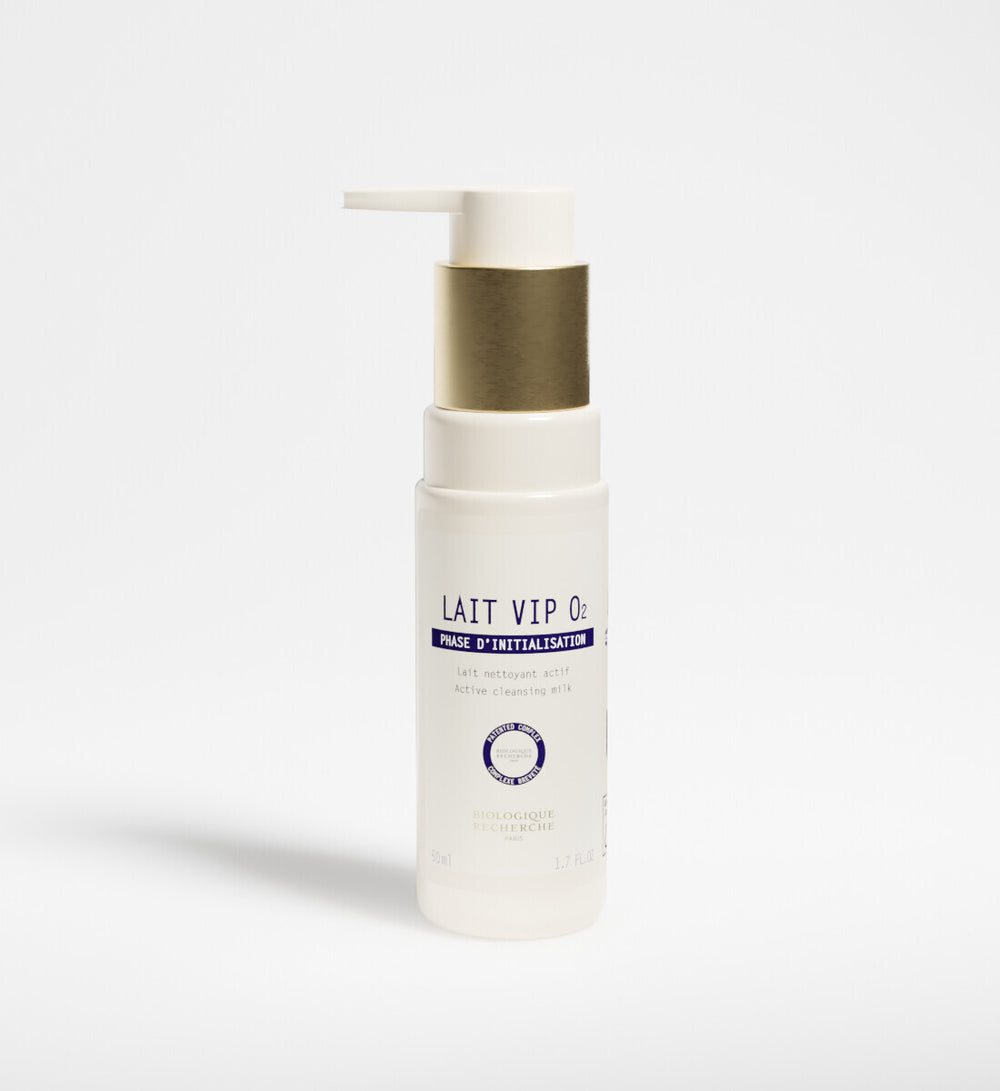 A white bottle of New Formula - Lait VIP 02 Cleansing Milk with a gold pump dispenser, featuring the signature VIP O2 Complex, stands upright on a plain white background.