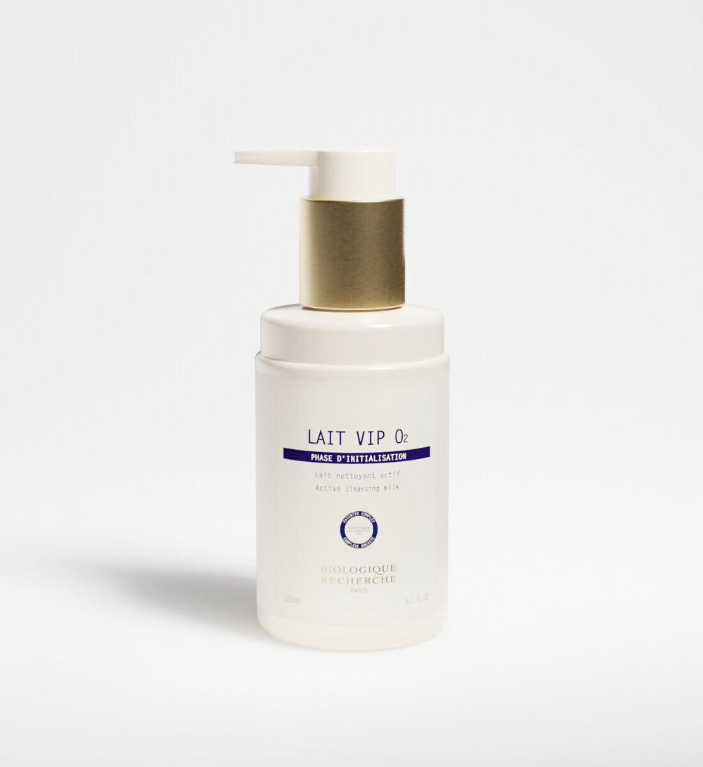 A white bottle of New Formula - Lait VIP 02 Cleansing Milk with a gold pump dispenser, featuring the signature VIP O2 Complex, stands upright on a plain white background.