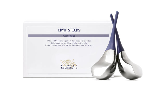 A set of metallic Cryosticks with dark handles sits stylishly in front of a white box labeled "BIOLOGIQUE RECHERCHE PARIS" and "CRYOSTICKS." This skincare tool is ideal for reducing redness, adding a soothing element to your beauty routine.