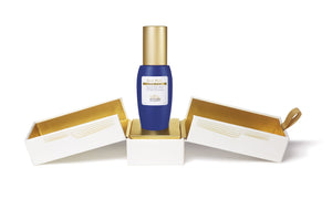 A bottle labeled "Biologique Recherche Silk Plus - 1 oz" is nestled between two open white and gold boxes, highlighting it as a blue and gold moisturizing serum infused with hyaluronic acid.