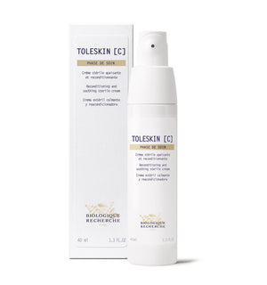 A bottle of Creme Toleskin reconditioning and soothing sterile cream, perfect for reducing skin sensitivity and redness, rests elegantly beside its box.