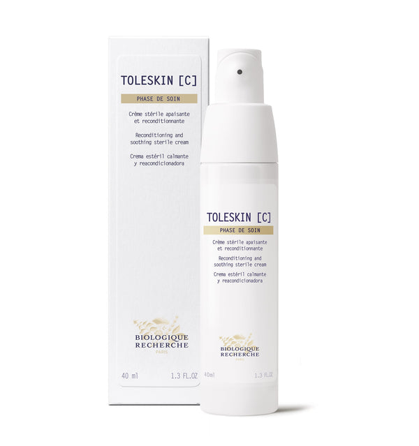 A bottle of Creme Toleskin reconditioning and soothing sterile cream, perfect for reducing skin sensitivity and redness, rests elegantly beside its box.